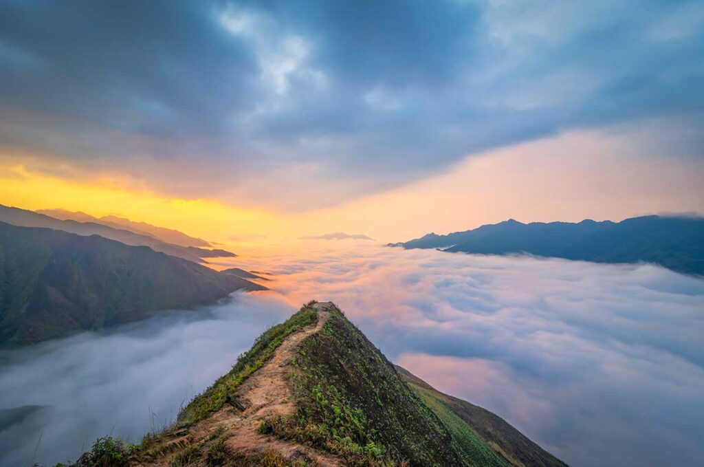 Famous Dinosaur Spine of Ta Xua - A dirt path leading over the edge of the mountain with valley view that is full of clouds