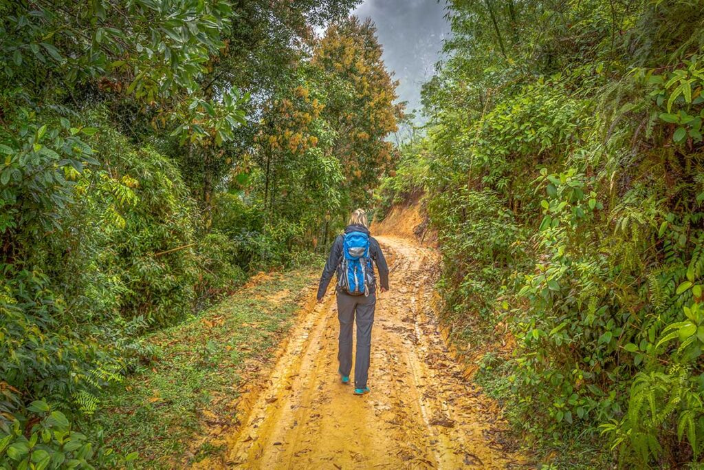 A woman Trekking in Pu Luong in jacket and muddy trails