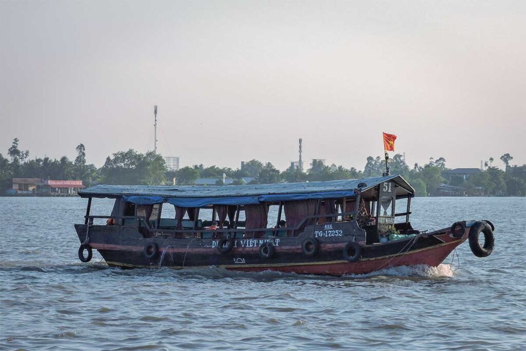 Traditional Mekong boat carrying passengers near Dragon Island (Tân Long), Vietnam.