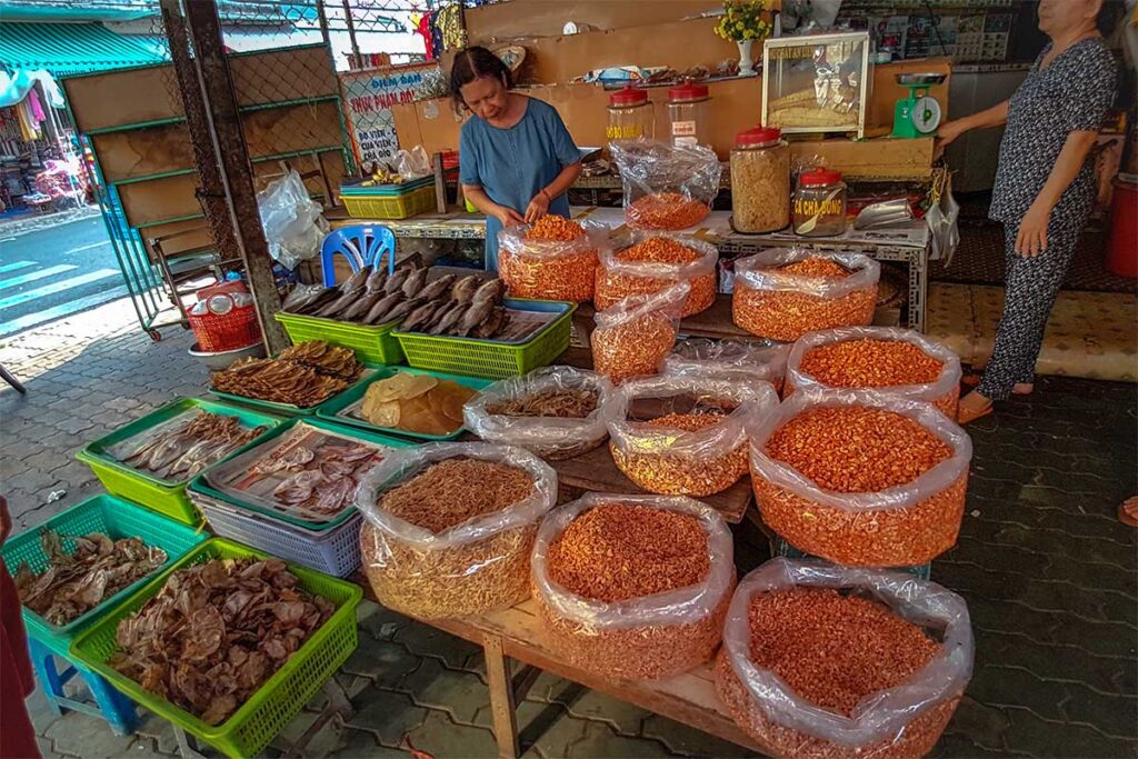 Vendor at My Tho Central Market selling dried shrimp, squid, and local spices