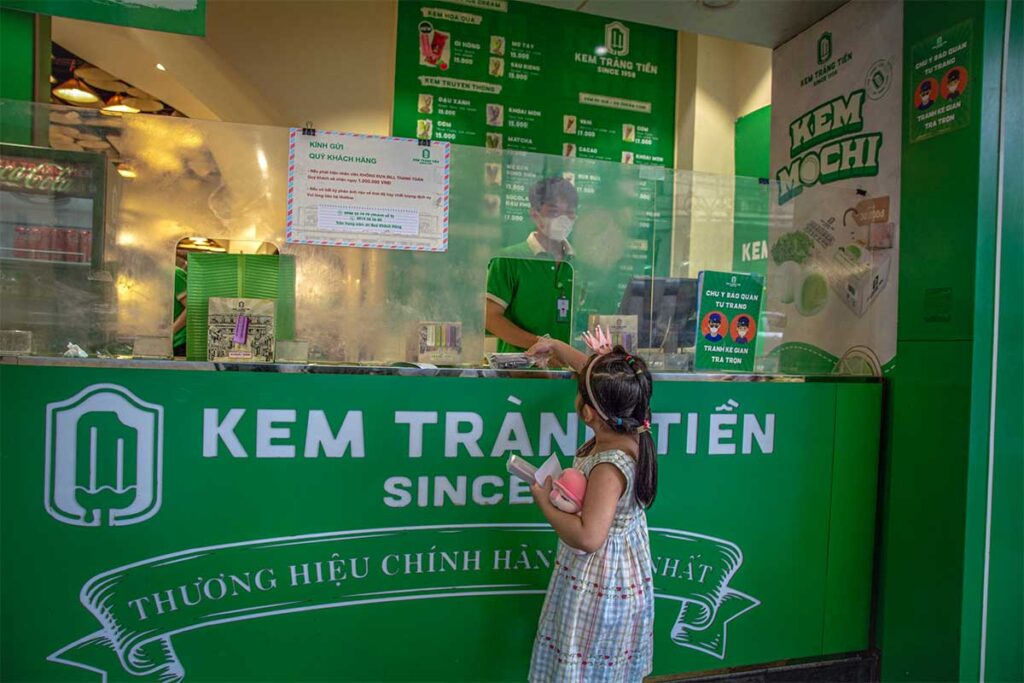 A little girl is paying for an ice cream at the counter of Trang Tien Ice Cream