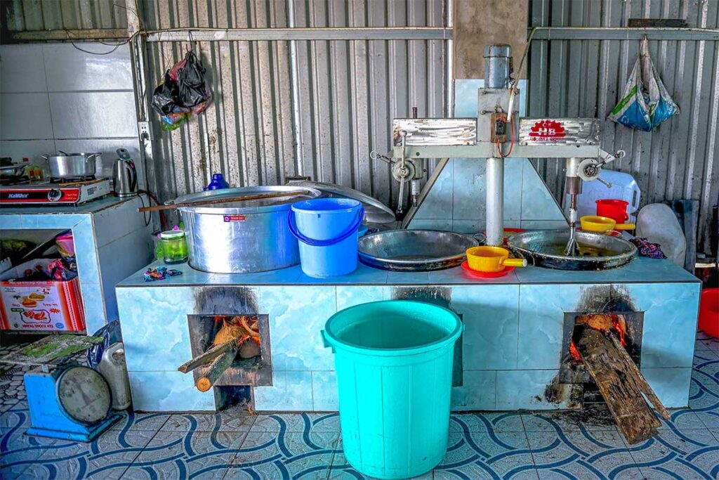 Rustic kitchen setup with wood-fired stoves and pans used for making coconut candy on Unicorn Island.