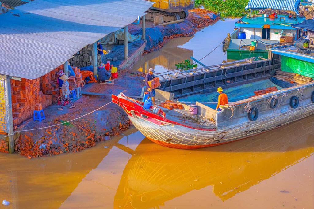 Workers loading bricks from riverside workshops onto boats in Mang Thit, Vinh Long