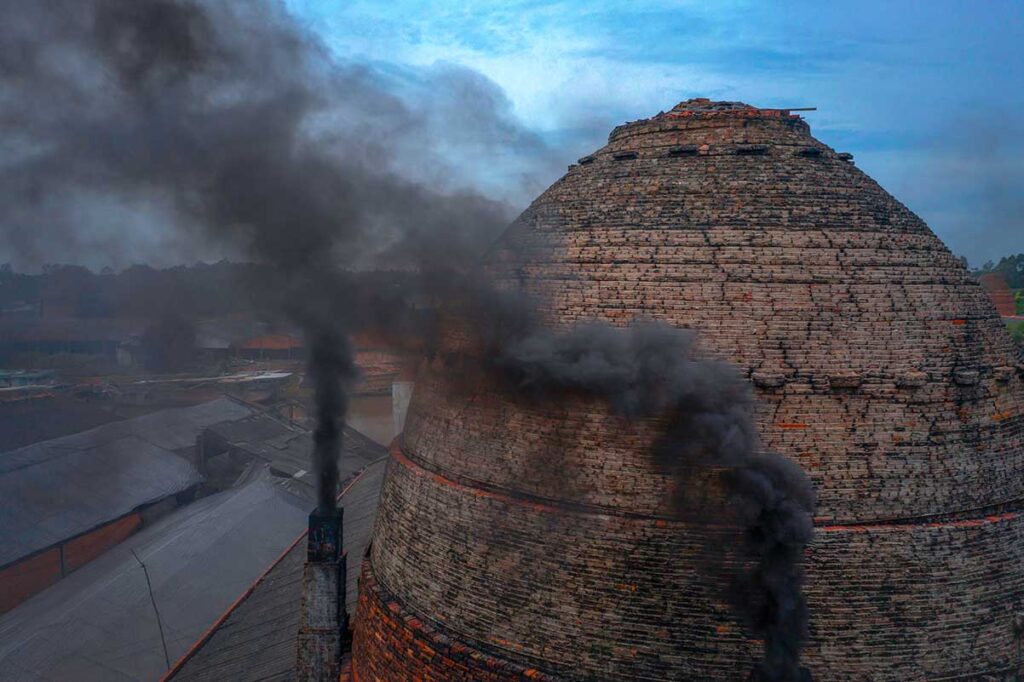 Close-up of a brick kiln chimney in Mang Thit releasing thick black smoke