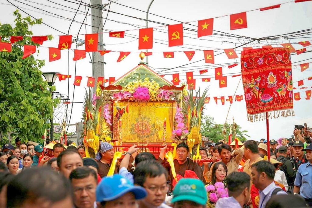 Crowds carrying the decorated palanquin of Ba Chua Xu Goddess during the festival procession at Sam Mountain in Chau Doc, Mekong Delta.