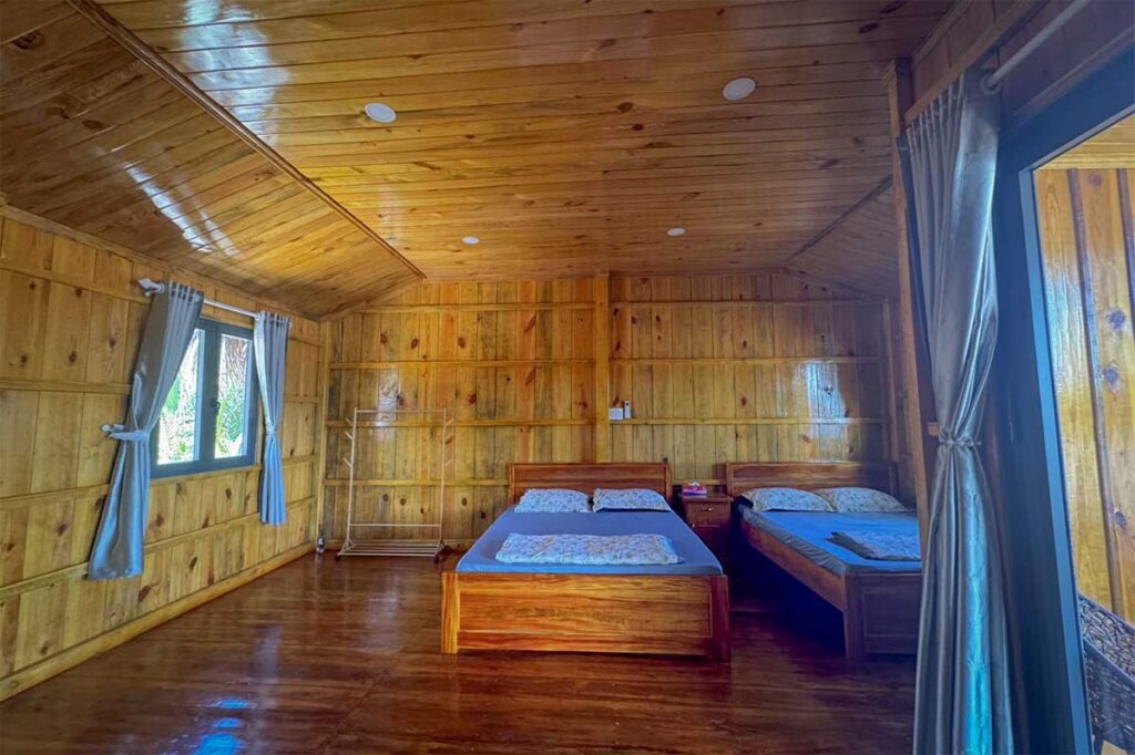 Simple wooden homestay room with two beds on Con Chim Island, Tra Vinh, offering rustic overnight stays for visitors