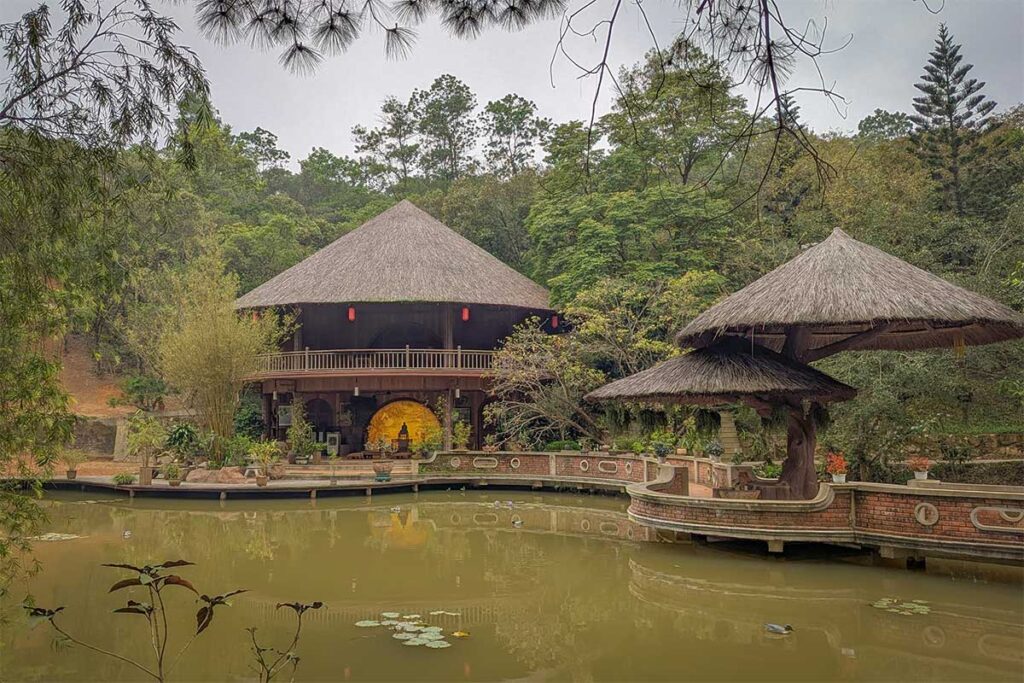 Am May Tia (Purple Cloud Hut) at Huyen Khong Son Thuong Pagoda in Hue, a large wooden hall with thatched roof overlooking a lotus pond, used for calligraphy, poetry, and meditation.