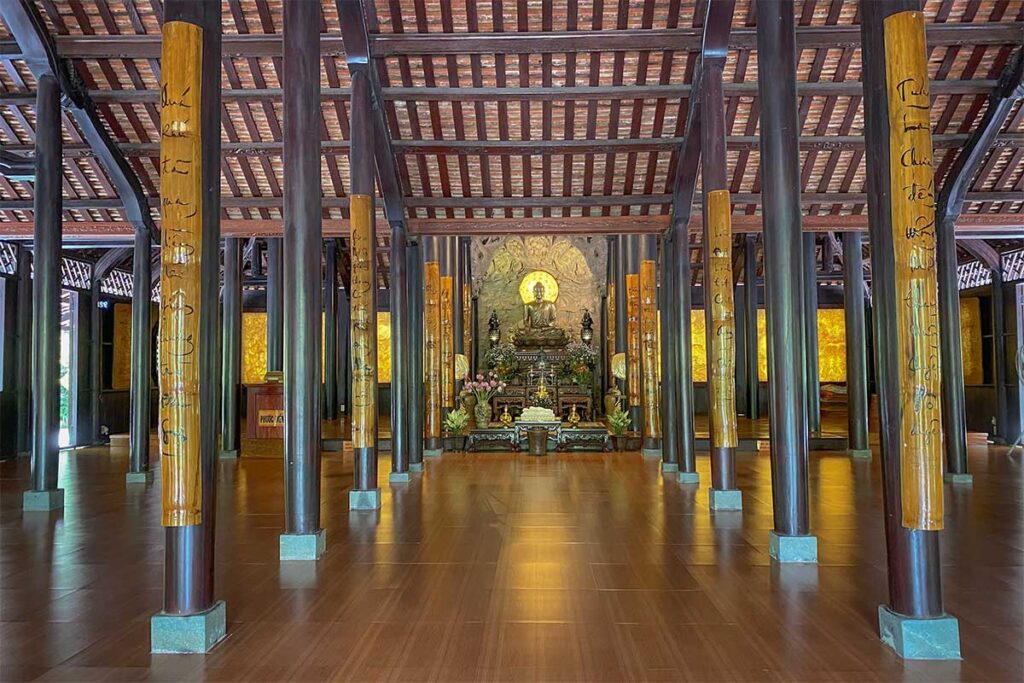 Interior of the wooden main hall at Huyen Khong Son Thuong Pagoda, featuring calligraphy columns and a central Buddha altar.