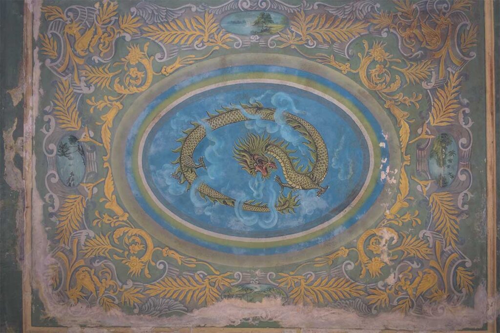 Ornate ceiling painting of a dragon surrounded by floral motifs inside Huynh Ky Ancient House, Tra Vinh.