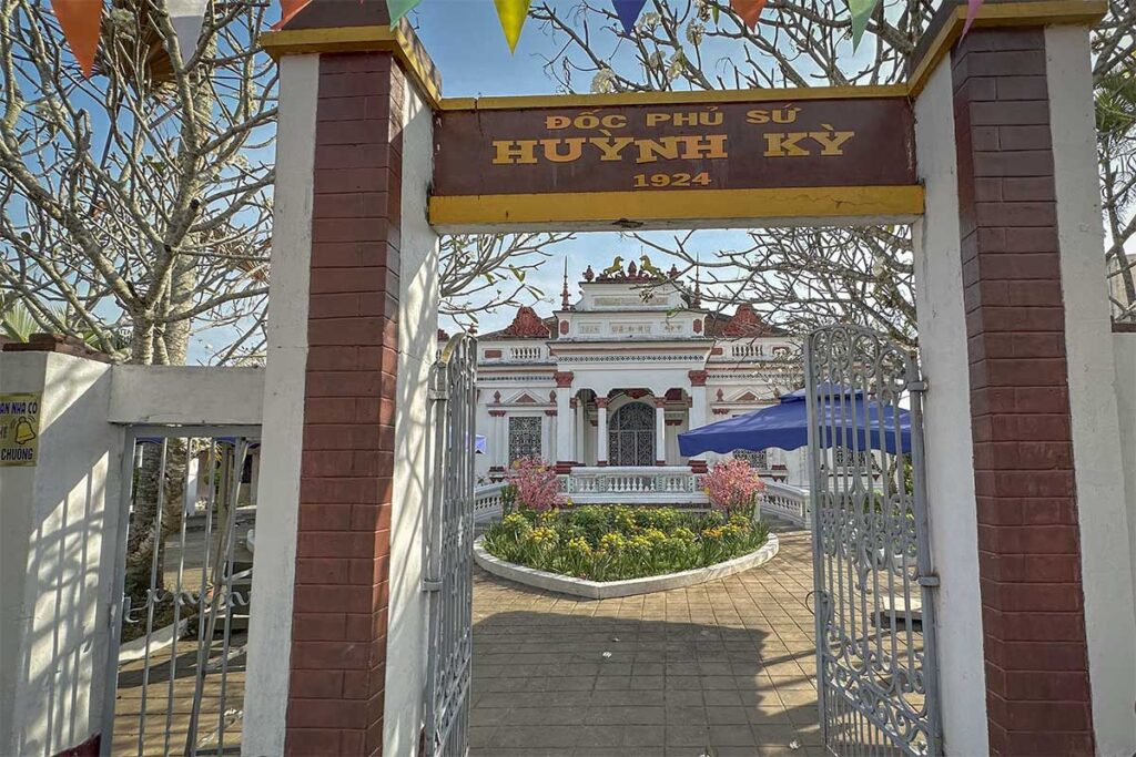 Entrance gate to Huynh Ky Ancient House in Tra Vinh with 1924 inscription and view of the mansion beyond.