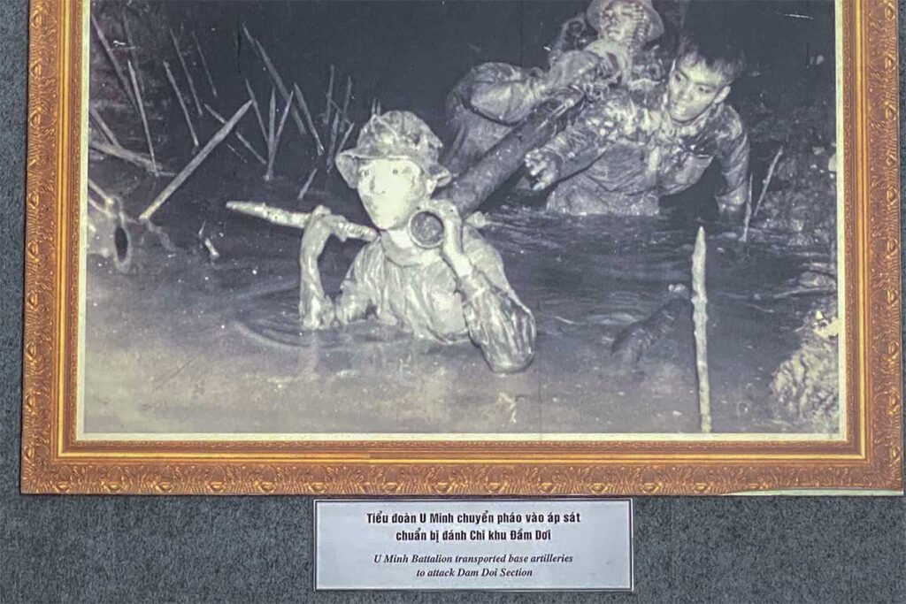 Black and white photo of U Minh Battalion soldiers moving through swamps with artillery, on display at Military Zone 9 Museum