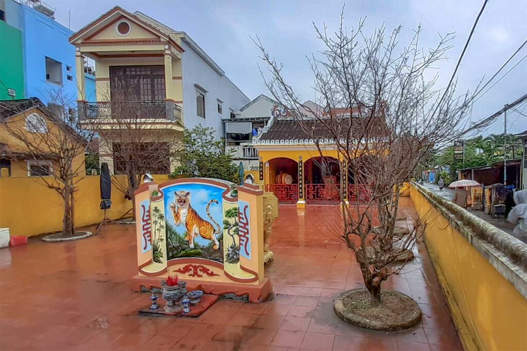 Tiger Temple (Ong Cop Temple) near Tan An Market in Hoi An with tiger mural, altar, and traditional yellow walls.