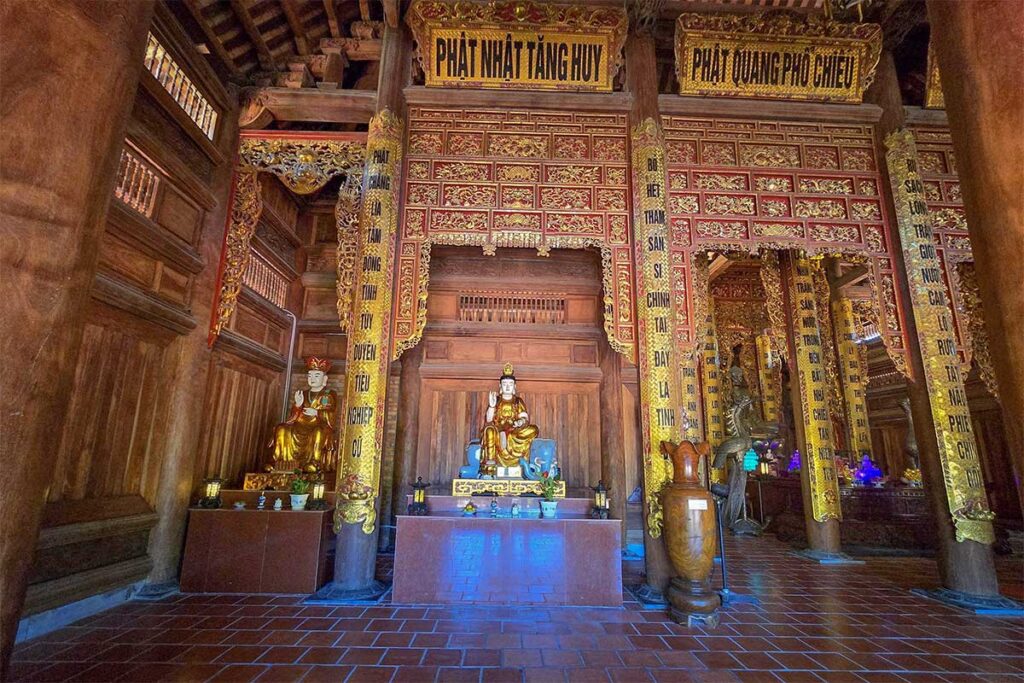 Wooden interior of Truc Lam Zen Monastery in Tra Vinh with golden Buddha statues and ornate carvings, offering a peaceful atmosphere for visitors.