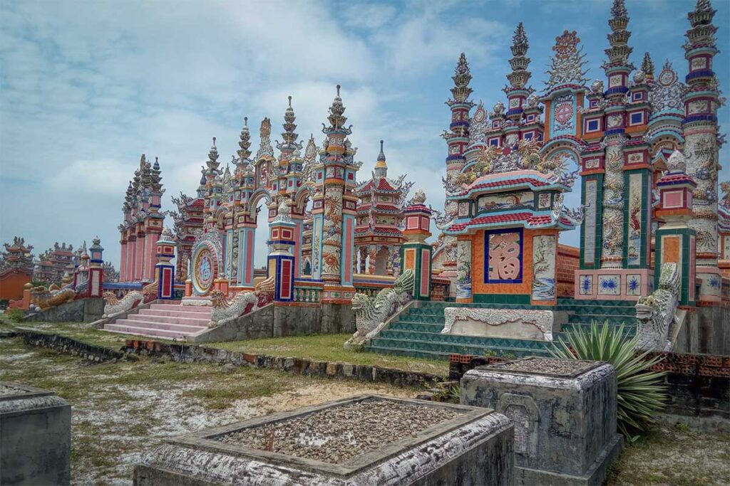 Close-up of ornate archways and colorful ceramic details inside An Bang Cemetery, revealing dragons, phoenixes, and religious symbols in mosaic style.