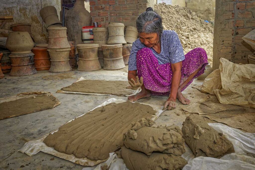 Elderly Cham woman preparing clay sheets for pottery making in Bau Truc Pottery Village, Ninh Thuan.