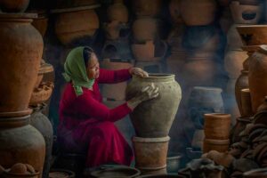 Cham artisan shaping a large clay jar by hand in a smoke-filled workshop at Bau Truc Pottery Village.