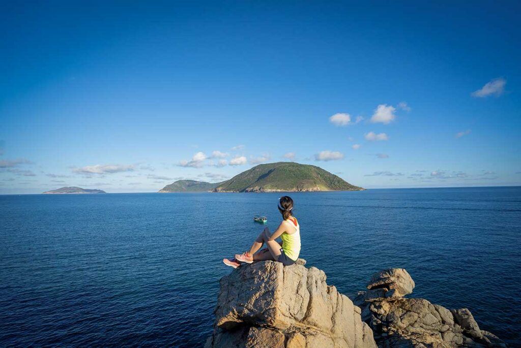 Authentic Con Dao tours by Local Vietnam | traveler enjoying sea view from rocky cliffs overlooking Con Dao Islands