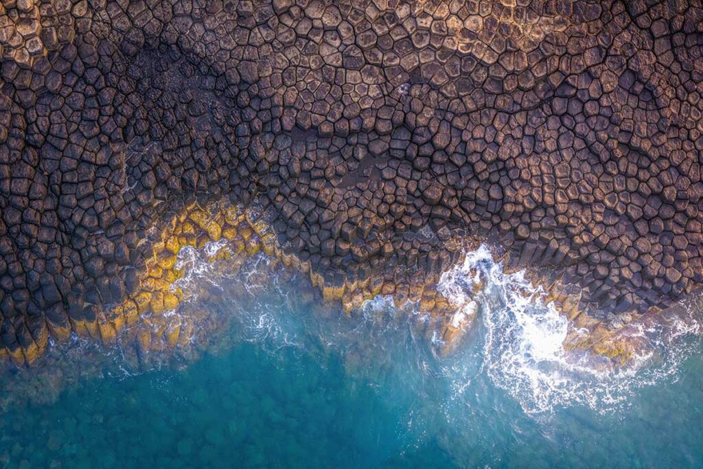 Aerial view of Da Dia Reef’s hexagonal basalt rock formations and turquoise sea on the Phu Yen coast of Vietnam.