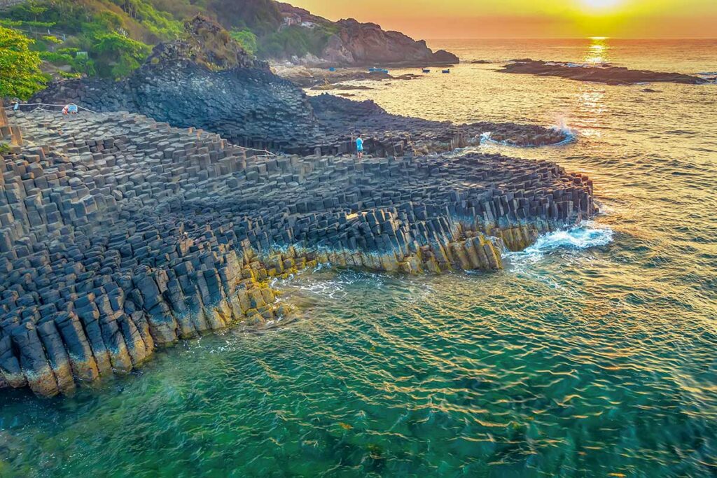 Golden sunset over the basalt formations of Da Dia Reef on the Phu Yen coastline of Vietnam.