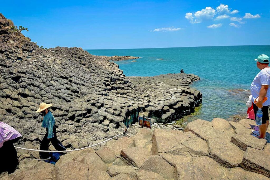 Visitors exploring the basalt columns at Da Dia Reef in Tuy An District, Phu Yen, Vietnam. Pathway to Da Dia Reef fishing bay