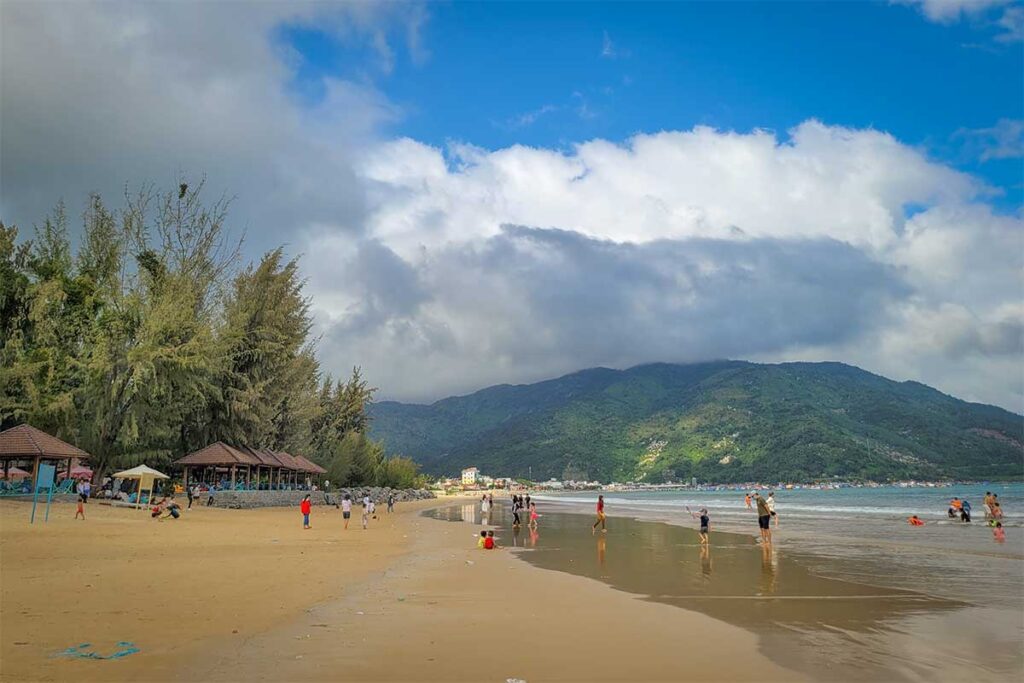 Dai Lanh Beach at the foot of Ca Pass – Golden sand and calm waters of Dai Lanh Beach, a popular swimming spot at the southern end of Ca Pass, with mountain views in the background.