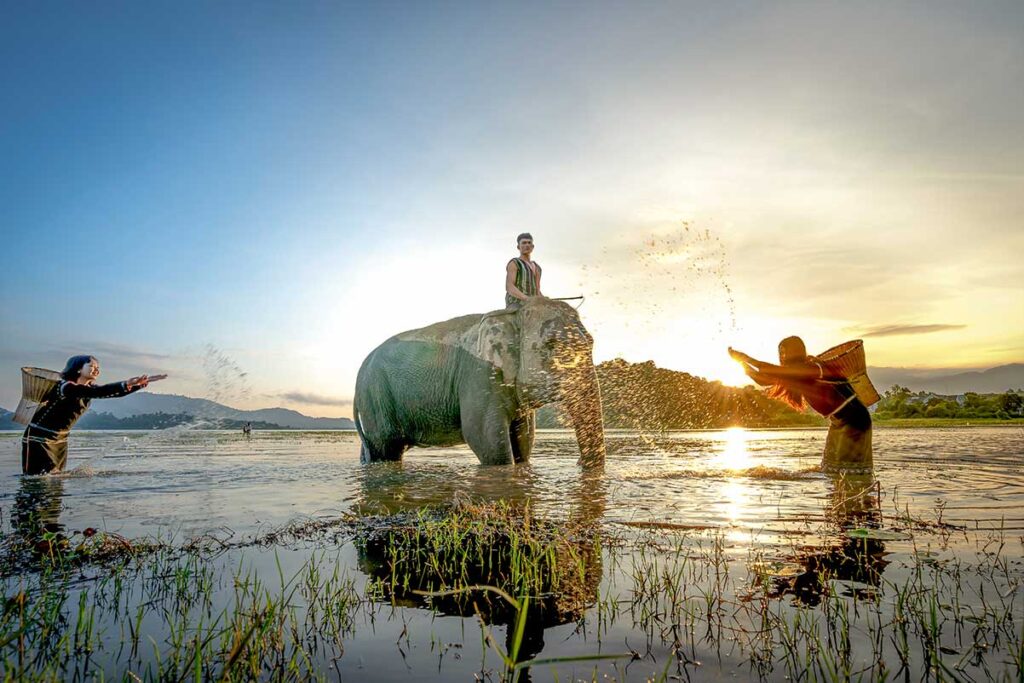 Dak Lak tours – Local Vietnam | ethnic villagers playing with an elephant at sunset in Vietnam’s Central Highlands