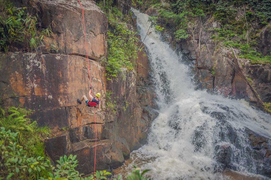 Dalat tours – Local Vietnam | traveler abseiling down a waterfall during a canyoning adventure in Vietnam’s Central Highlands