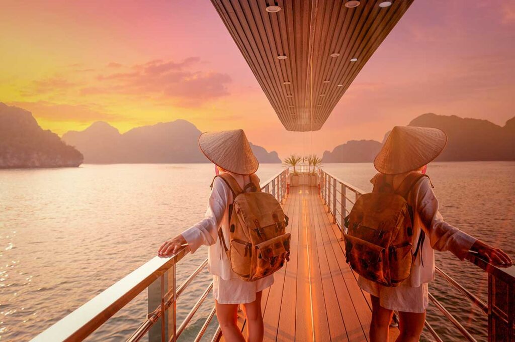Halong Bay cruise – Local Vietnam tours | traveler enjoying sunset views from a boat deck surrounded by limestone islands
