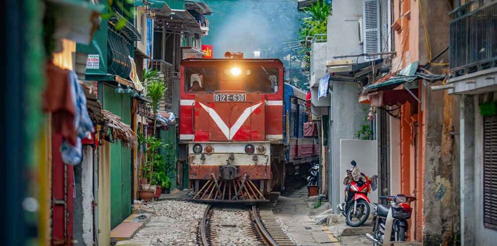 Hanoi tours – Local Vietnam | train passing through the narrow Hanoi Train Street surrounded by houses and cafés in the Old Quarter