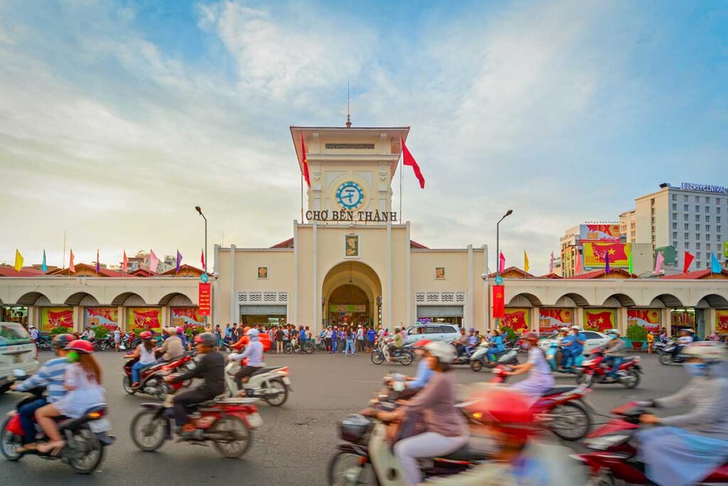 Ho Chi Minh City tours – Local Vietnam | busy motorbike traffic in front of Ben Thanh Market in Saigon’s historic city center