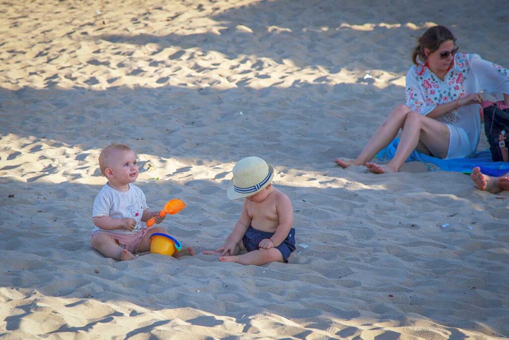 Babies playing with sand toys on a sunny beach in Hoi An, Vietnam