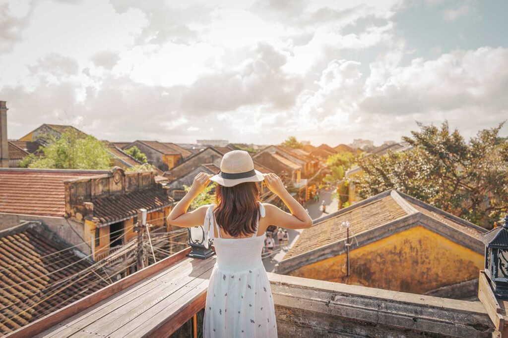 Hoi An tours – Local Vietnam | traveler enjoying the view over Hoi An Ancient Town rooftops in the golden afternoon light