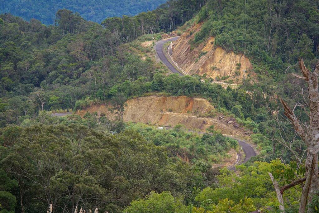 Winding mountain road cutting through steep forested hillsides in Hon Ba Nature Reserve.