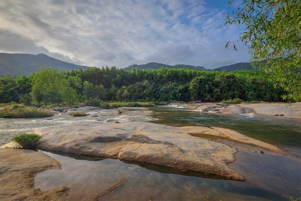 Stream with smooth rocks and green forest backdrop in Hon Ba Nature Reserve, Khanh Hoa – a peaceful stop for swimming and picnics near Nha Trang.