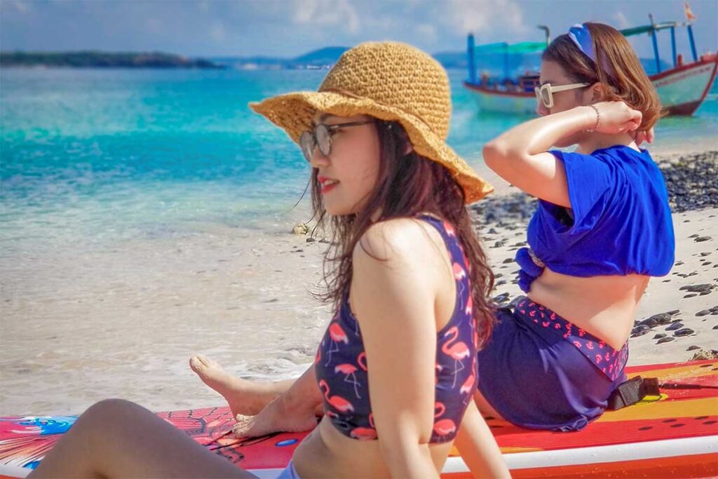 Visitors relaxing on paddleboards at Hon Chua Island, enjoying the turquoise water and white sandy shore near Long Thuy Beach in Phu Yen.