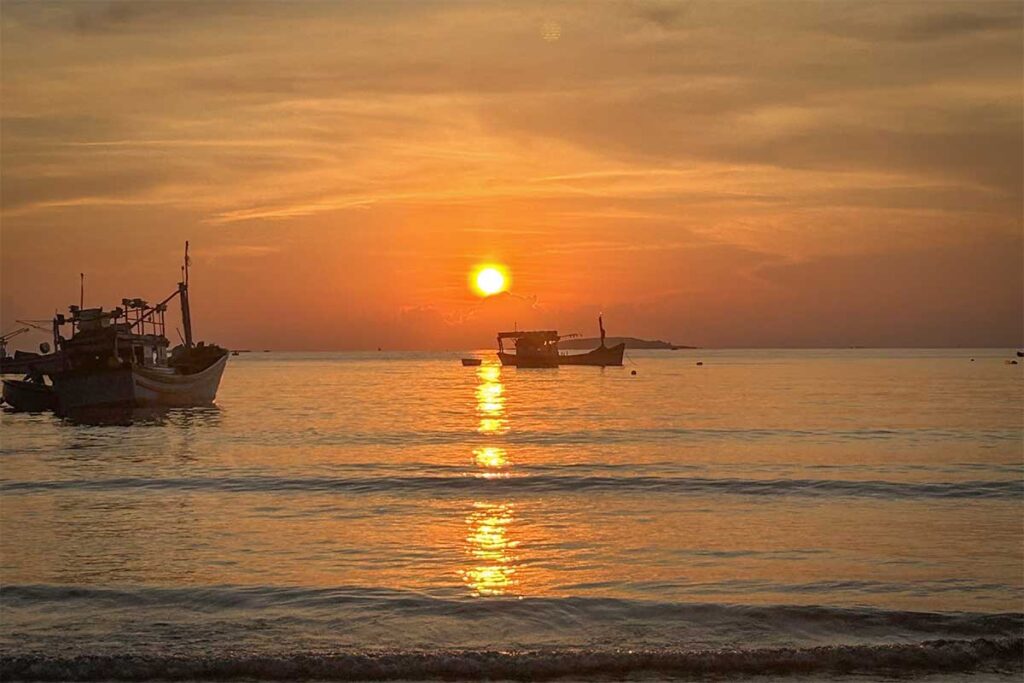 Traditional fishing boats at sunrise in Long Thuy – Colorful boats anchored close to shore as the rising sun reflects off the gentle waves.