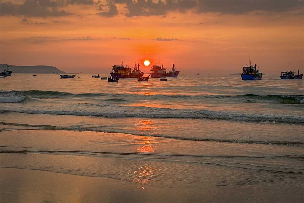 Fishing boats at sunrise on Long Thuy Beach – Traditional wooden boats returning at dawn, with the sun rising over calm waves on the Phu Yen coast.