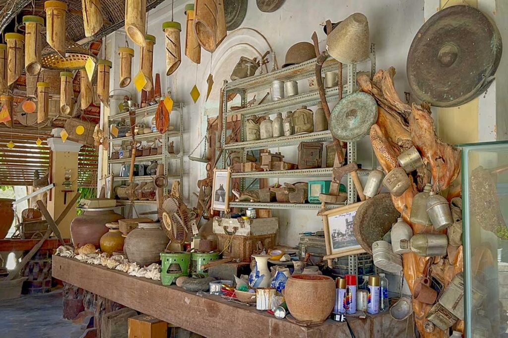 Collection of old household tools, pottery, and coral artifacts displayed in the museum-like house near Mang Lang Church.