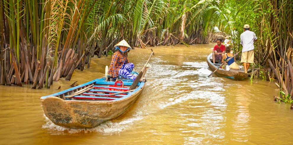 Mekong Delta Vietnam – Local Vietnam tours | local boat rowers navigating narrow palm canals with visitors on a Mekong Delta day trip