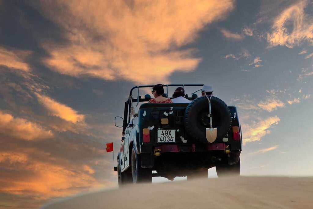 Jeep tour at Nam Cuong Sand Dunes during sunset with golden sky in Phan Rang, Ninh Thuan