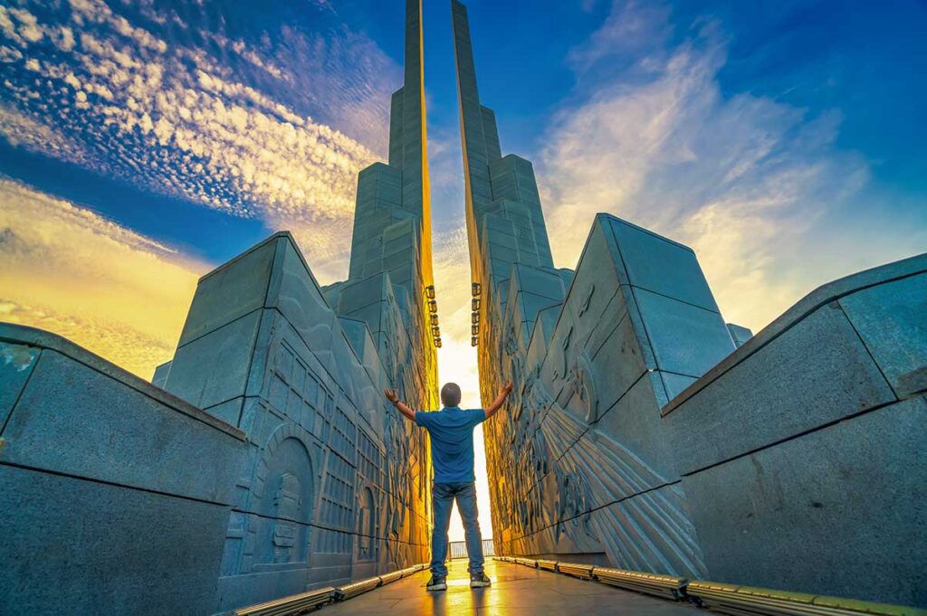 Visitor standing in the wind gap of Nghinh Phong Tower as sunlight streams through the stone columns.