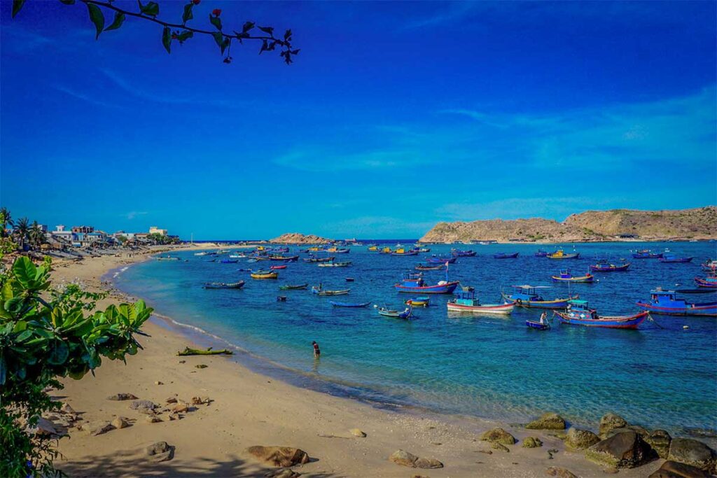 Beach in Nhơn Hải with colorful fishing boats – Sandy shoreline and calm waters where traditional wooden boats line up along the coast of Nhơn Hải fishing village.