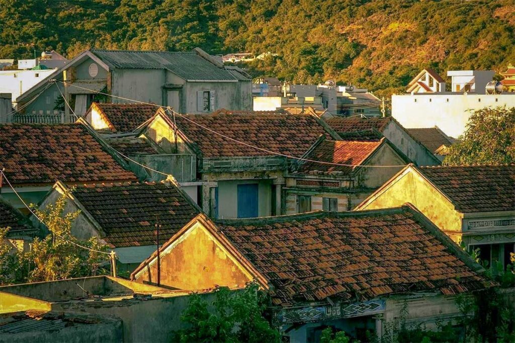 Sunset light over red-tiled rooftops of Nhon Ly fishing village on the Phuong Mai Peninsula, Quy Nhon.