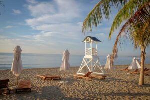 Empty sun loungers and lifeguard tower on Ninh Chu Beach, Phan Rang, during a calm morning.