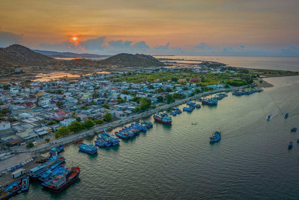 Aerial view of Ninh Chu fishing port at sunset, with a fleet of fishing boats and the coastal village of Phan Rang