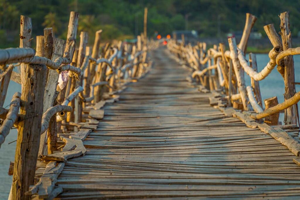 Close-up of Ong Cop Wooden Bridge planks and bamboo railings in Phu Yen, Vietnam, showing the rustic and uneven surface that rattles under motorbikes.