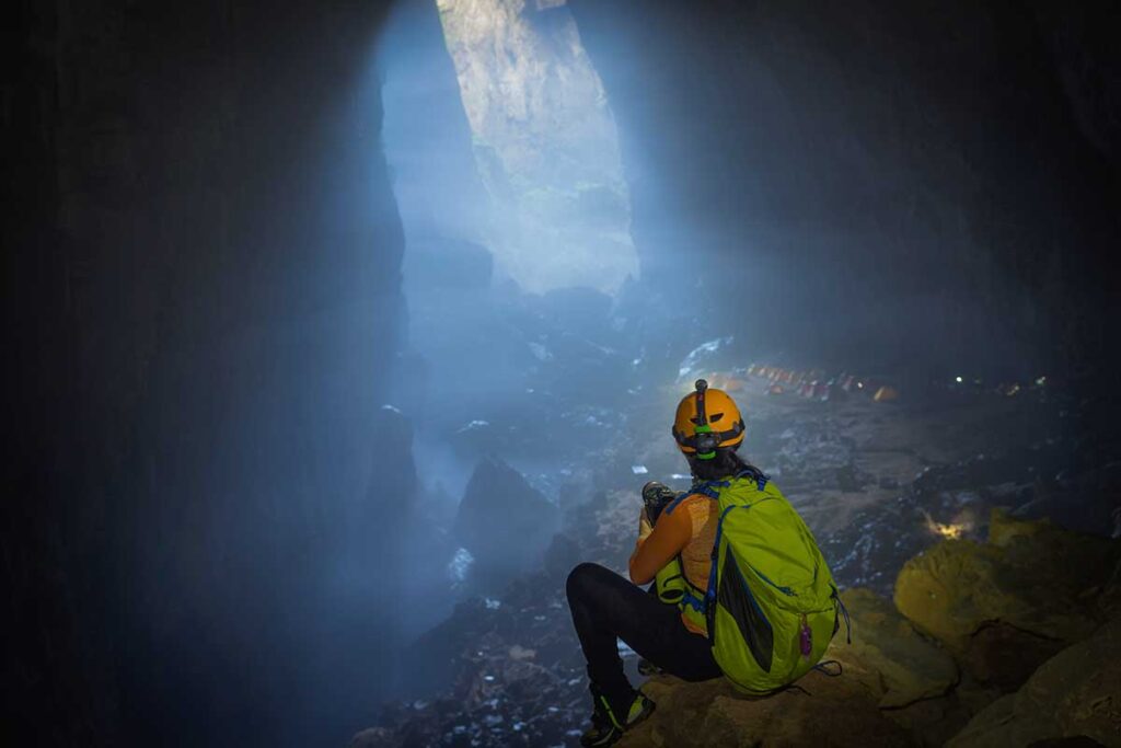 Phong Nha tours – Local Vietnam | explorer with helmet and backpack inside a giant cave in Phong Nha-Ke Bang National Park, Vietnam