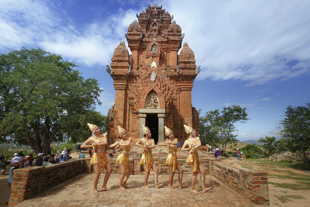 Cham dancers performing in traditional golden costumes in front of Po Klong Garai Tower during the Kate Festival in Phan Rang, Vietnam.