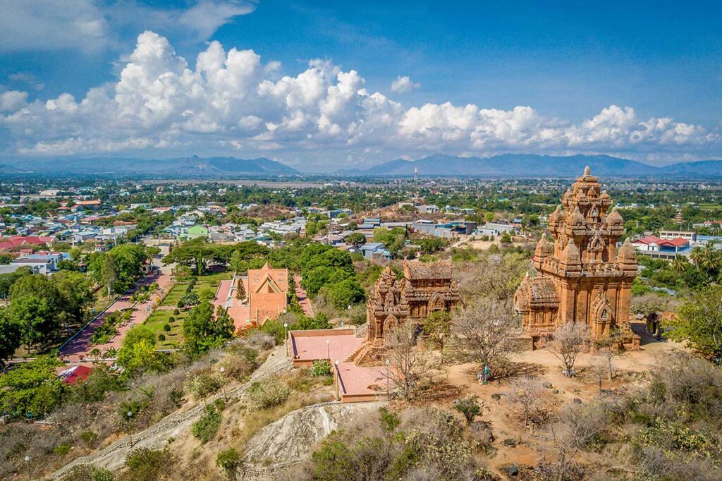 Aerial view of Po Klong Garai Cham Towers on Trau Hill overlooking Phan Rang city with mountain ranges in the distance.