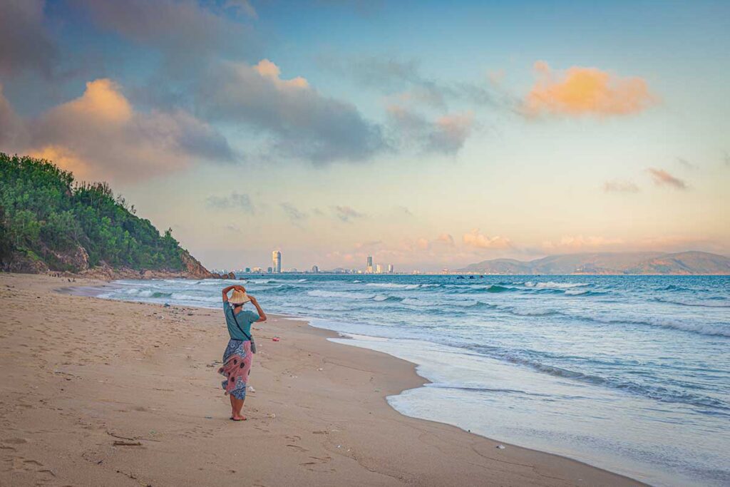 Quy Hoa Beach, Quy Nhon: quiet sandy bay facing the city skyline, calm water and soft evening light.